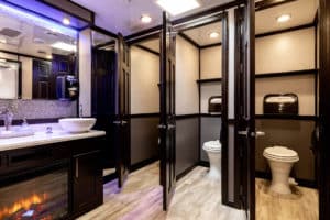 Luxury Restroom Trailer Rental, 10-Station VIP Restroom Trailer, inside view of fireplace, sinks and women’s restroom stalls from Major Event Trailers in Ventura, CA.